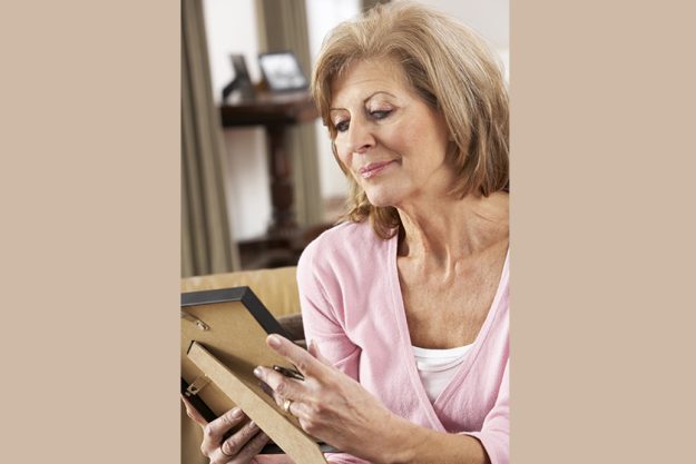 senior woman looking at photograph in frame