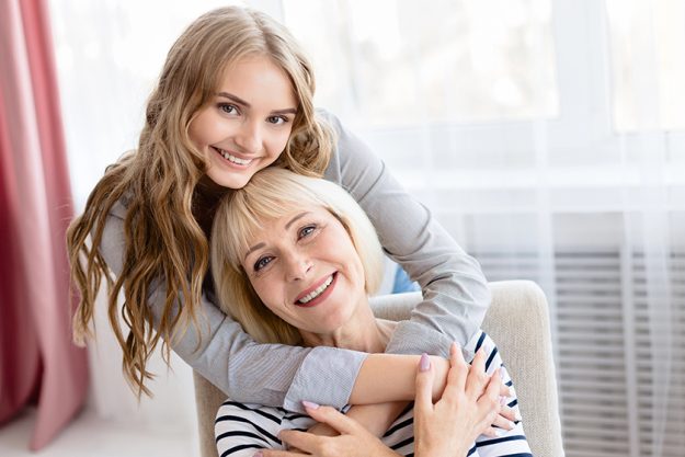 young daughter cuddling her senior mother with love