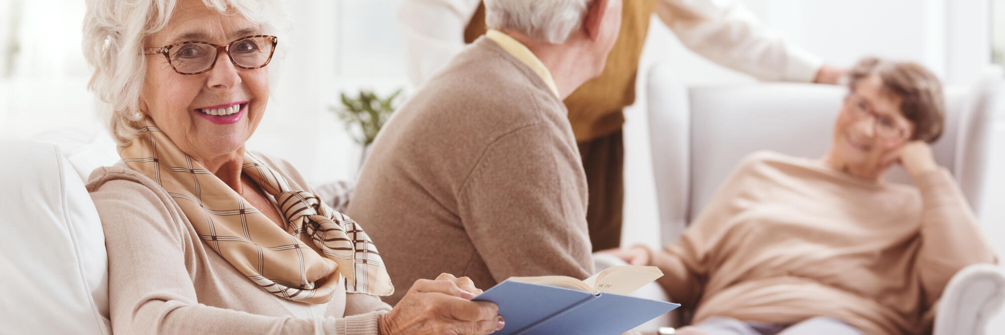 Elderly,Woman,Reading,A,Book,And,Her,Friends,Chatting,With