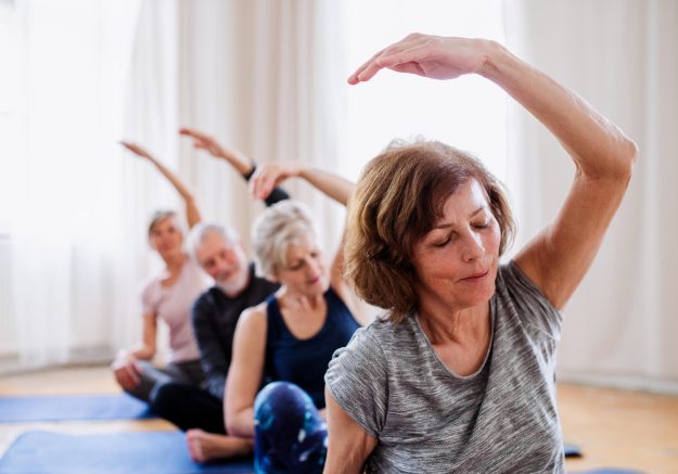 Group,Of,Senior,People,Doing,Yoga,Exercise,In,Community,Center
