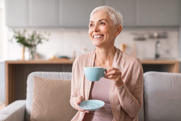 attractive mature lady drinking fresh coffee tea sitting modern living
