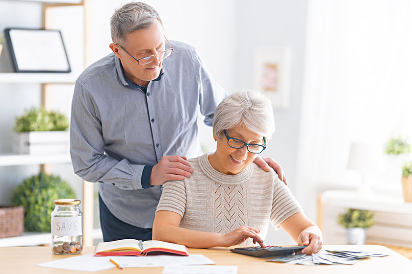 elderly married couple sitting desk paper receipt hands calculating expenses