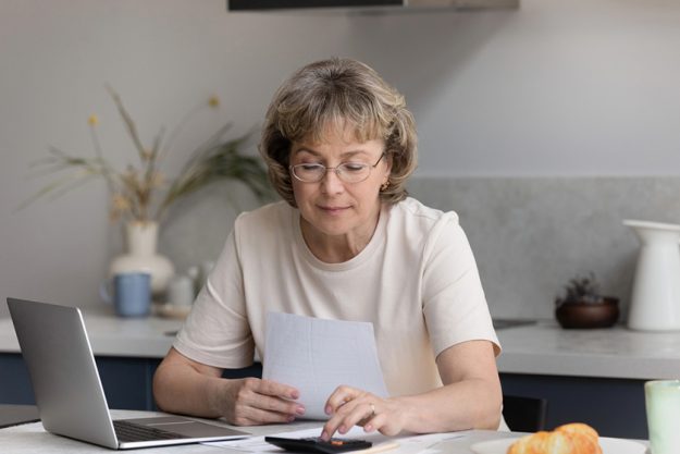 focused middle aged woman calculating bills at home