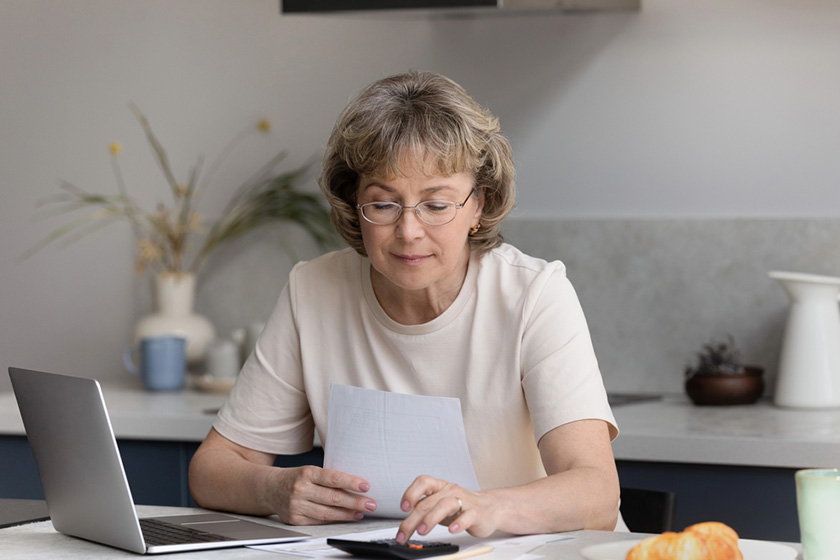 focused middle aged woman calculating bills at home focused middle aged woman calculating bills at home