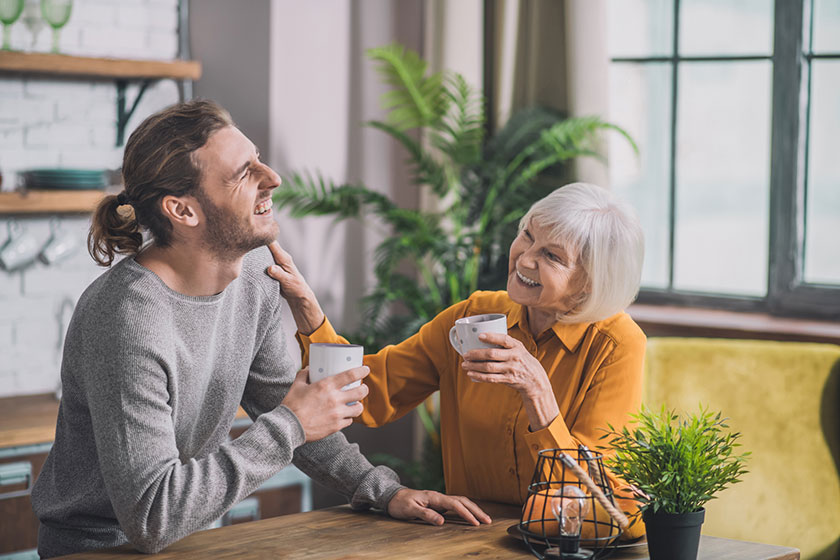 grey haired mom and her son having coffee together