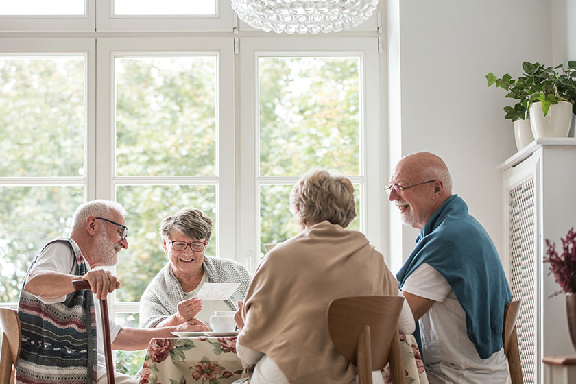 group of senior friends sitting together at the table at nursing home dining room