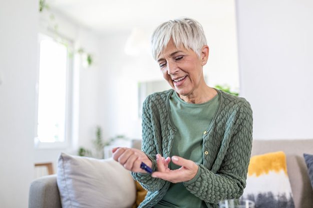 mature woman testing high blood sugar woman holding device measuring
