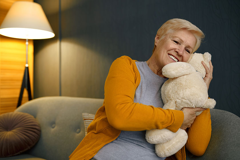 old woman hugging teddy bear on sofa