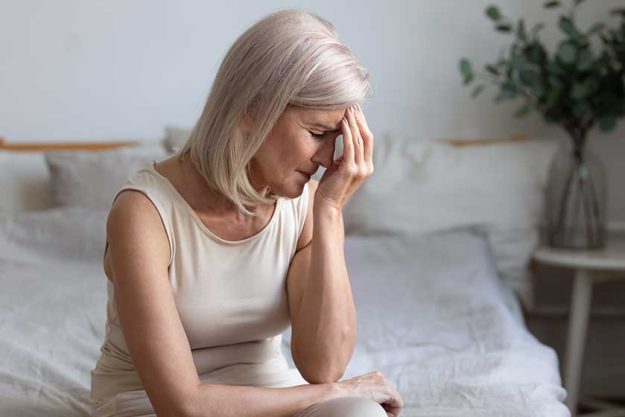 older woman sit on bed coping with morning headache concept older woman sit on bed coping with morning headache concept