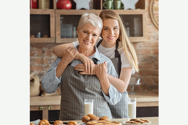 portrait of adult mother and daughter embracing at kitchen portrait of adult mother and daughter embracing at kitchen