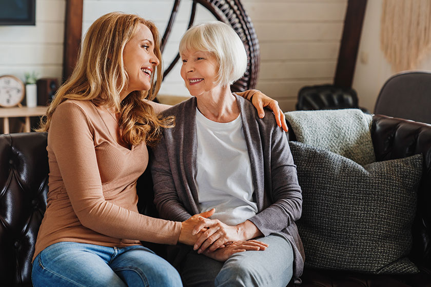 senior mother adult daughter hugging each other sofa living room