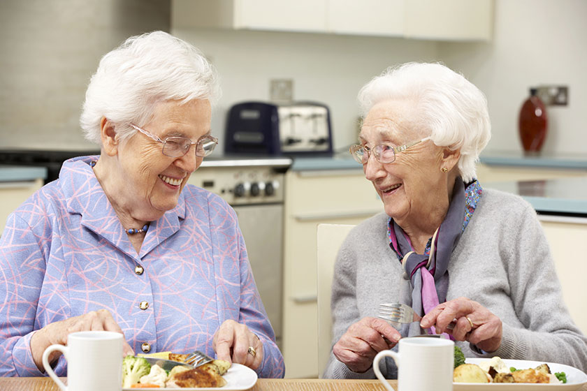 senior women enjoying meal together at home