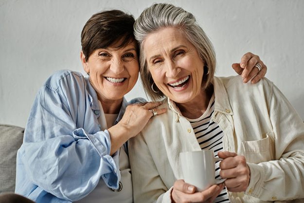 two older women loving mature lesbian couple sit together couch