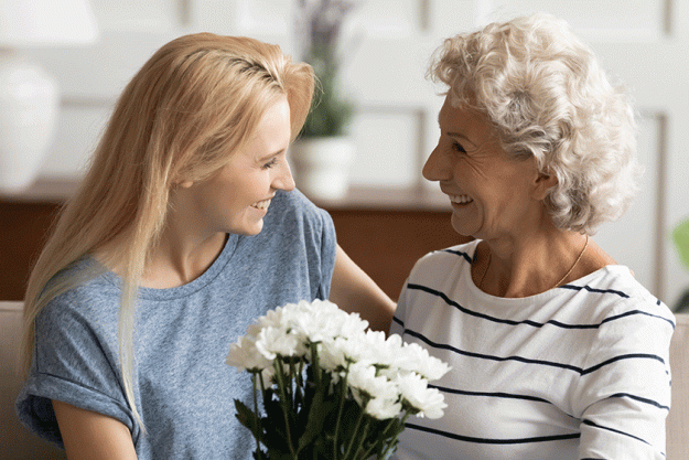 young smiling blonde grown up daughter congratulating happy mother