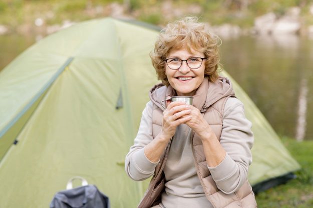 Happy mature female hiker with hot drink