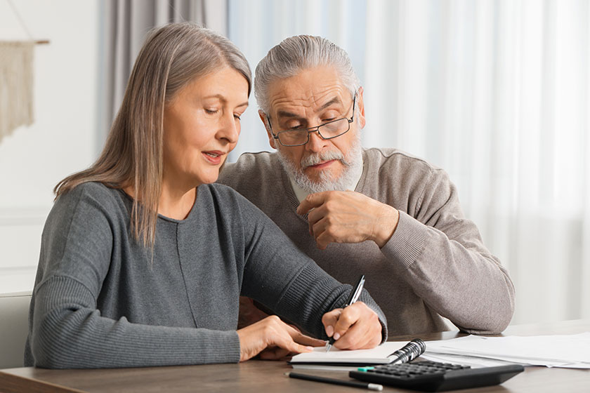 Elderly couple papers discussing pension plan wooden table indoors Elderly couple papers discussing pension plan wooden table indoors