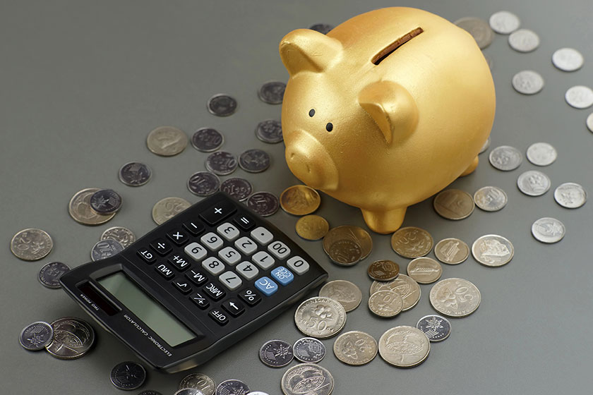 Golden piggy bank looking to calculator with coins financial concept