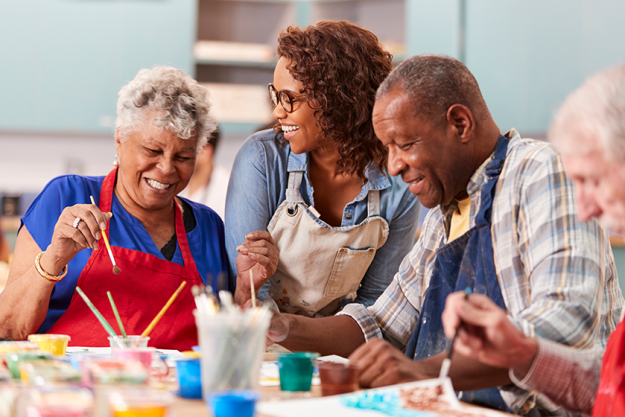 group retired seniors attending art class community centre teacher