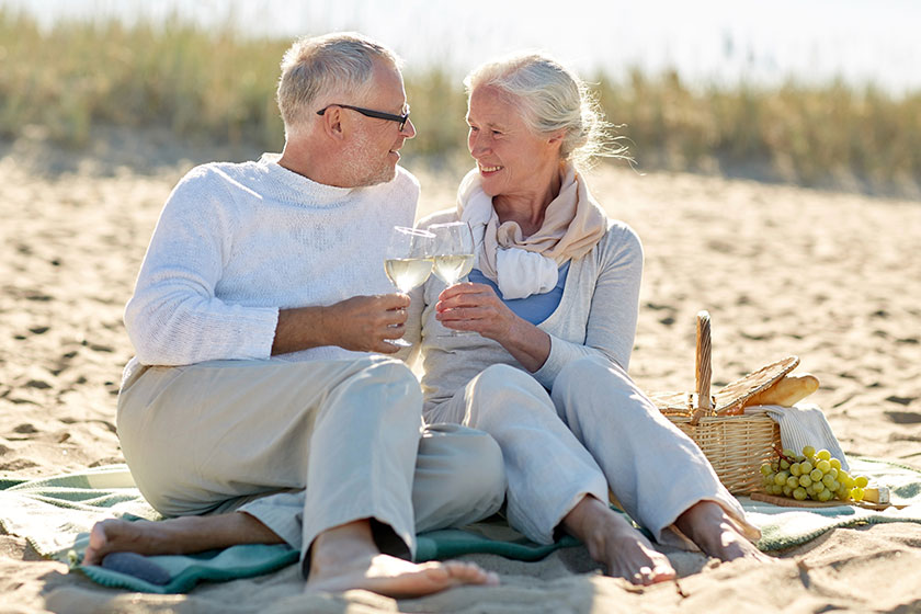 appy senior couple having picnic on summer beach