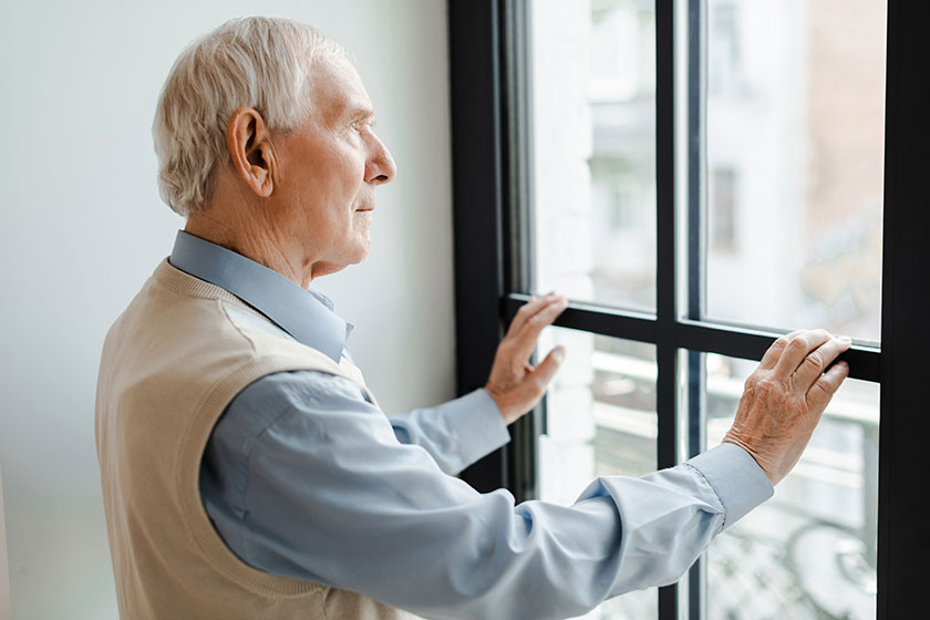 Sad elderly man looking window quarantine