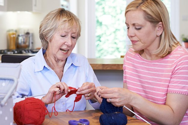 Senior and mature female friends knitting at home together Senior and mature female friends knitting at home together