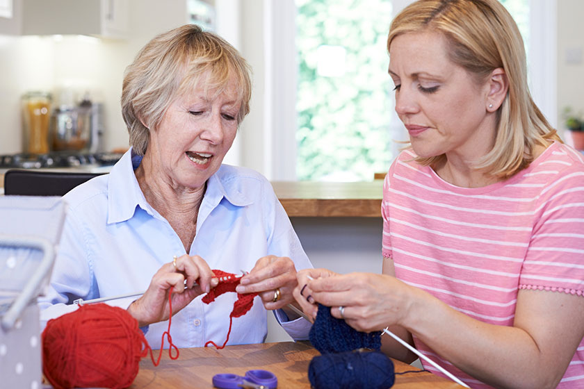 Senior and mature female friends knitting at home together