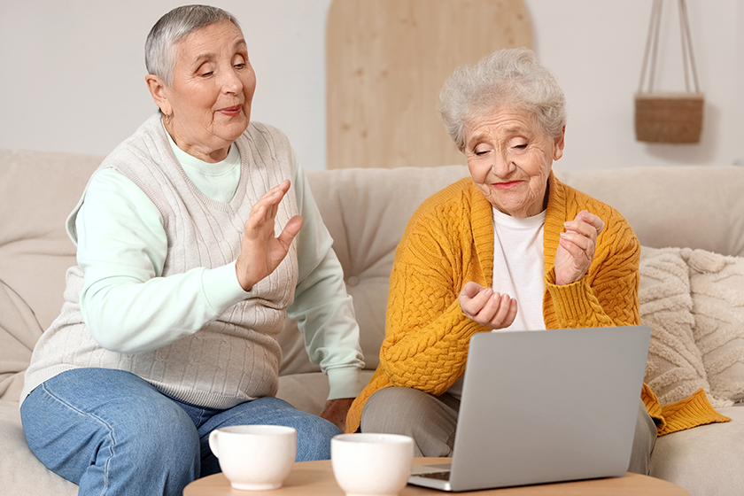 senior female friends laptop video chatting home