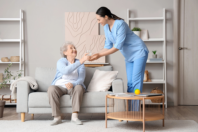 senior woman taking glass water physical therapist home