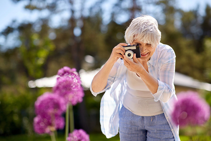 Senior woman with camera photographing flowers Senior woman with camera photographing flowers
