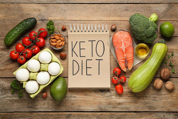 Notebook phrase keto diet different products wooden table flat lay