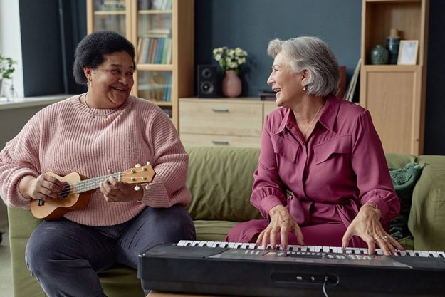 Portrait two joyful senior women playing music together enjoying creative