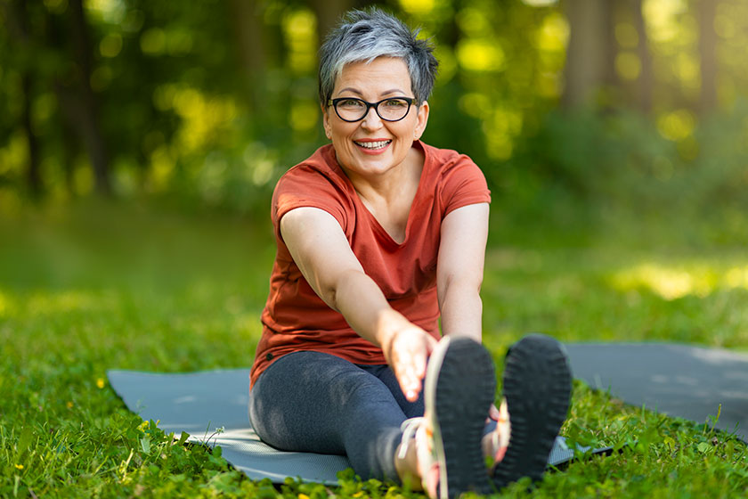 Beautiful happy senior woman training outdoors smiling older lady stretching