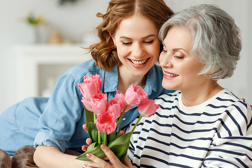 cheerful young female hugging happy aged mother giving bouquet tulips cheerful young female hugging happy aged mother giving bouquet tulips