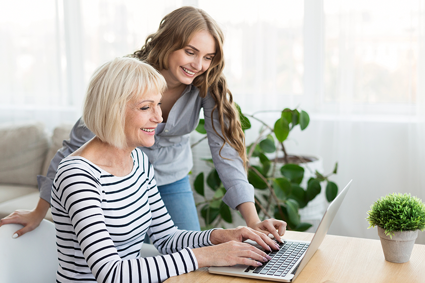 daughter teaching mother to use laptop