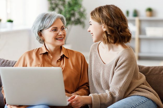 Happy aged woman young adult daughter smiling looking each other Happy aged woman young adult daughter smiling looking each other