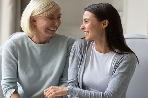 Happy elderly mother and adult daughter relax at home talking Happy elderly mother and adult daughter relax at home talking