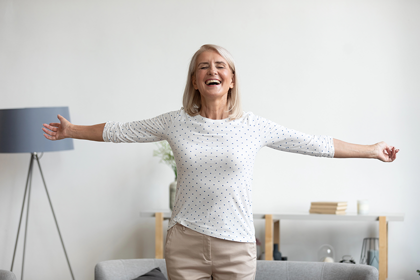 happy mature woman standing in living room