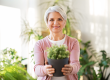 happy senior woman with flower in pot