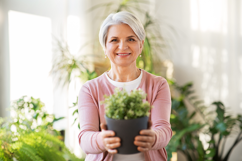 happy senior woman with flower in pot