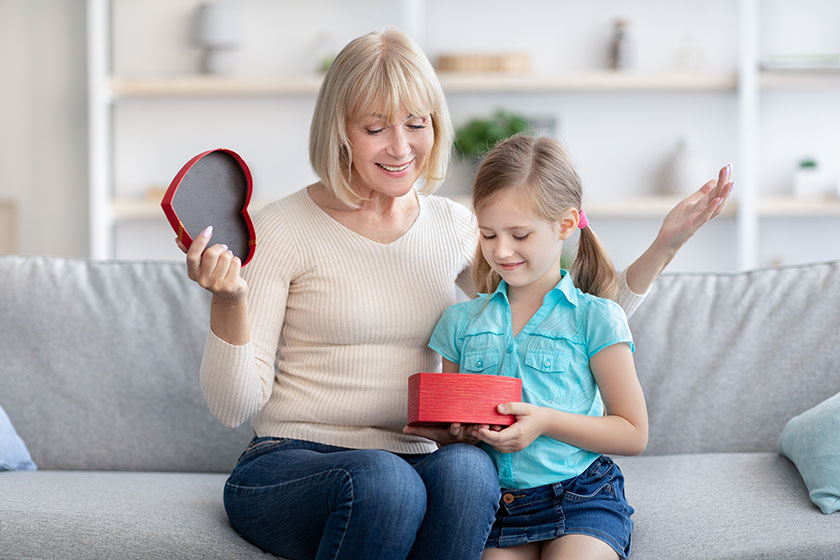 little girl greeting mature lady giving box