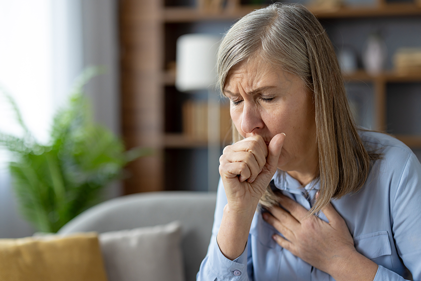 older woman looks distressed she coughs clutching her chest discomfort