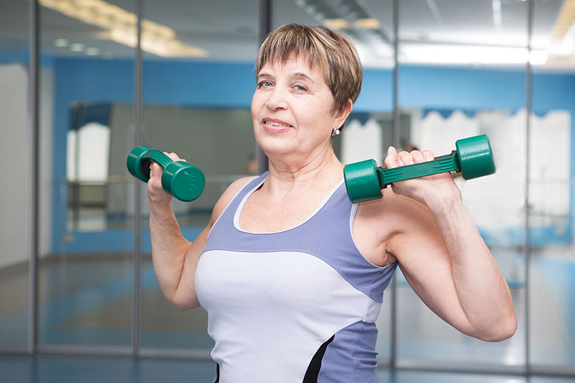 Portrait of pretty senior woman exercising with dumbbells