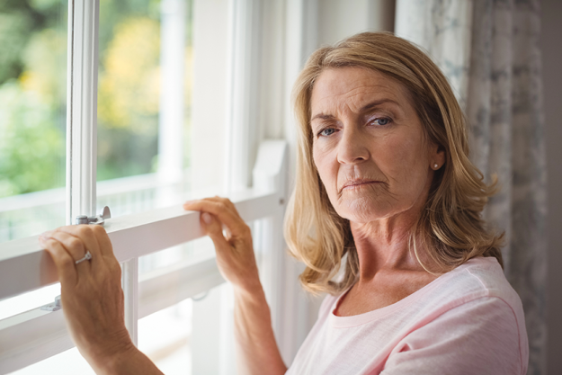 portrait of senior woman standing next to window