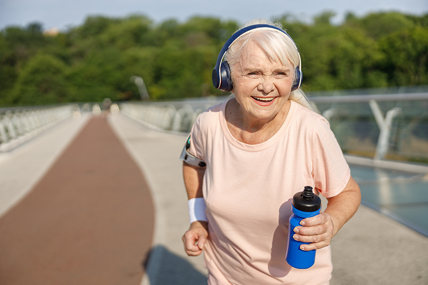 positive senior lady with headphones runs