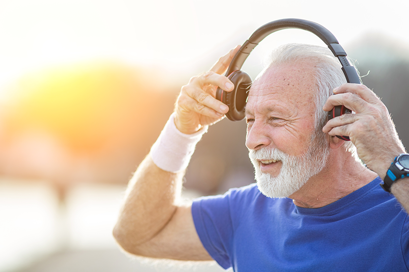 senior smiling man beard sportswear puts headphones