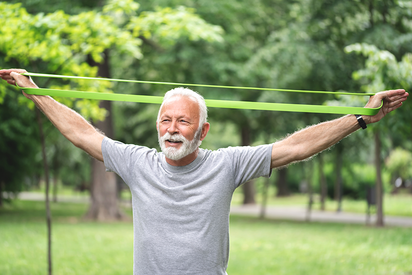 senior sportsman exercising resistance band