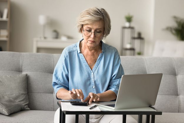 serious older mature woman eyeglasses counting savings calculator laptop doing serious older mature woman eyeglasses counting savings calculator laptop doing