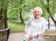 smiling senior woman standing railings park