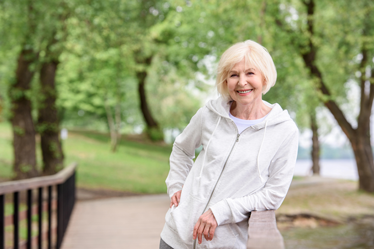 smiling senior woman standing railings park