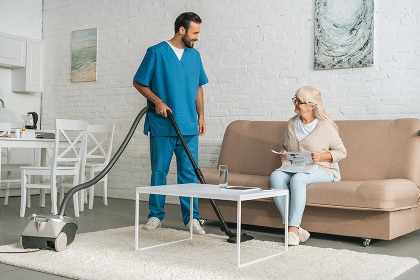 smiling social worker using vacuum smiling social worker using vacuum